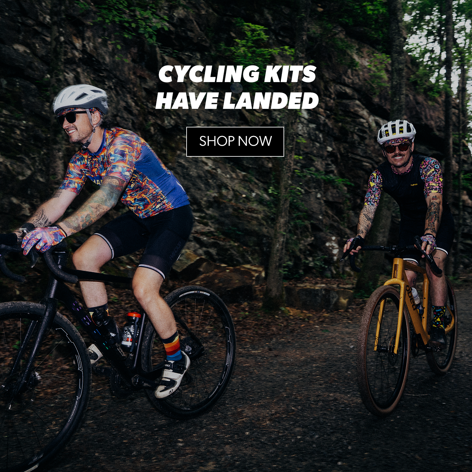 Two cyclists on a forest path with text overlay 'Cycling Kits Have Landed' and 'Shop Now'.