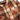 A close-up of a men's plaid flannel shirt , featuring a warm brown, beige, and rust-orange check pattern with dark buttons and a chest pocket.
