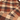 Close-up of a plaid flannel shirt fabric with a warm beige base, brown and rust-orange check pattern, and a small white 'WALK' brand label near the collar.