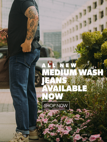 Person wearing medium wash jeans with promotional text overlay on a city street.