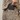 Person wearing a leopard print jacket with a phone in the pocket, holding a black phone case.