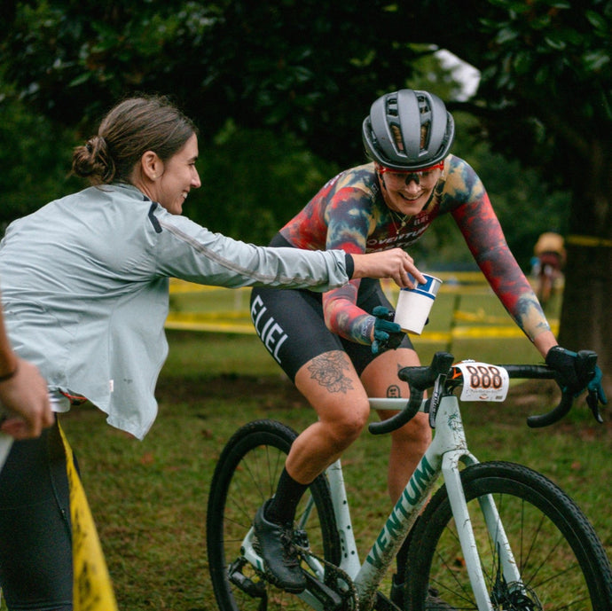 Cyclist receiving a drink from a support person during a race