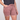 A person wearing dusty rose denim shorts with a frayed hem, paired with a dark sleeveless top, shown from the chest down against a light gray studio background.