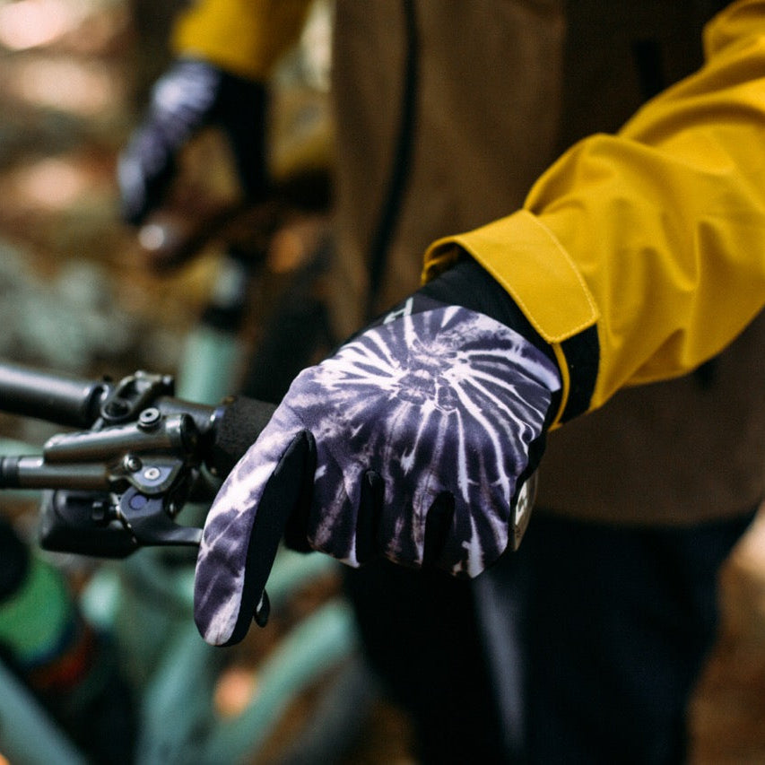 Person wearing a yellow jacket and purple gloves on a bike in a forest setting
