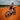 Person riding a bicycle on a red dirt road with a blue sky and clouds in the background