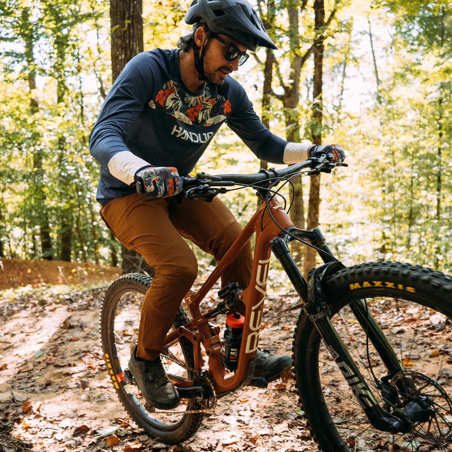 Man riding a mountain bike with a long sleeve jersey with the word 'Handup'