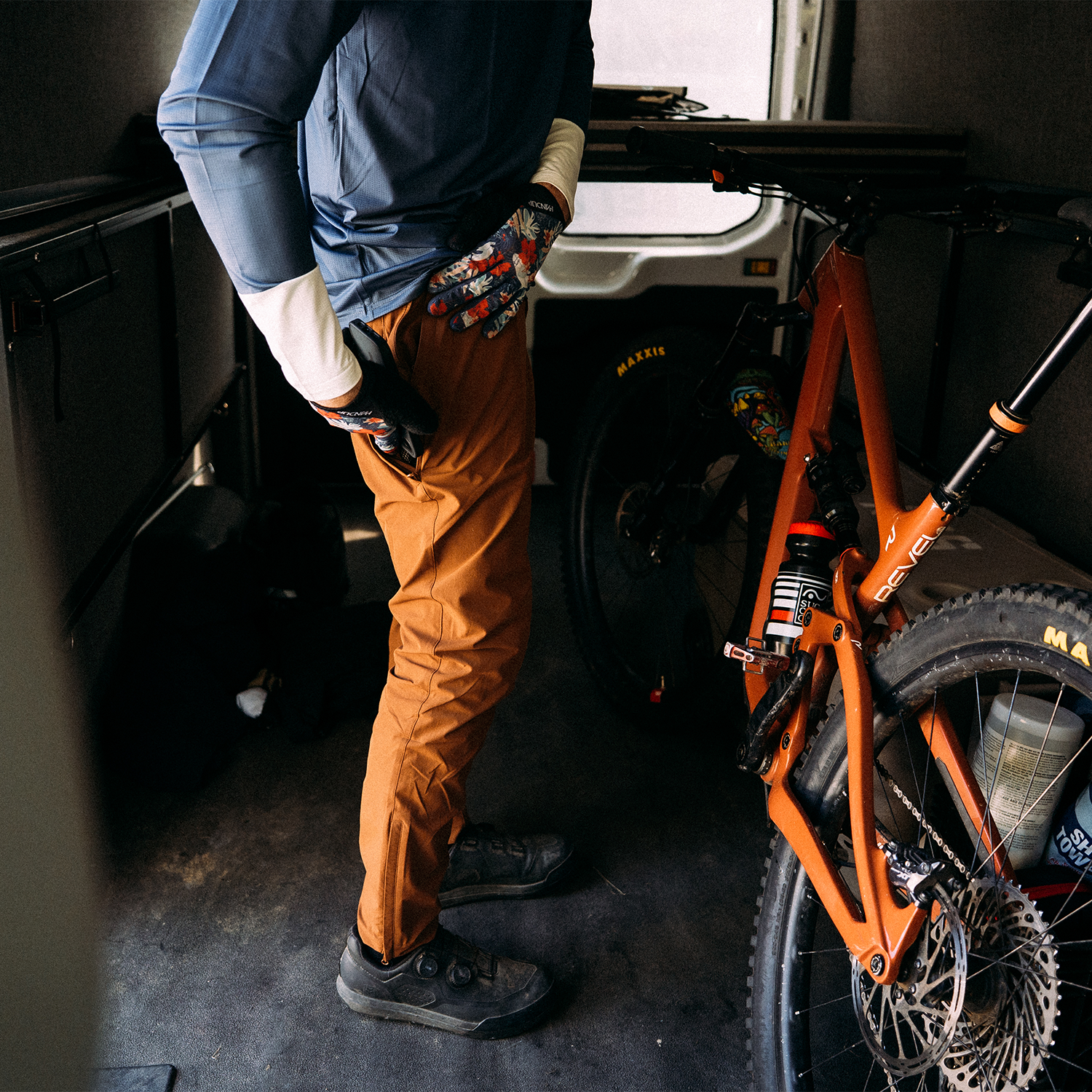 Person loading an orange mountain bike into a vehicle