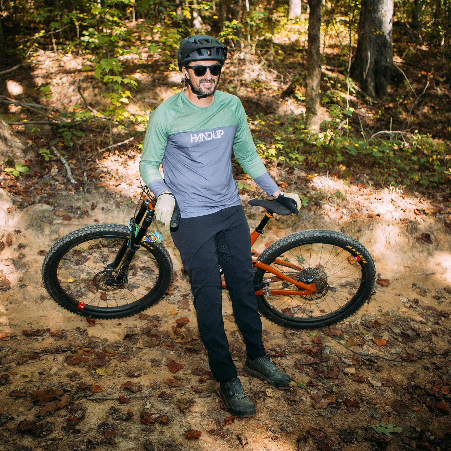 Man holding a mountain bike in a forest setting