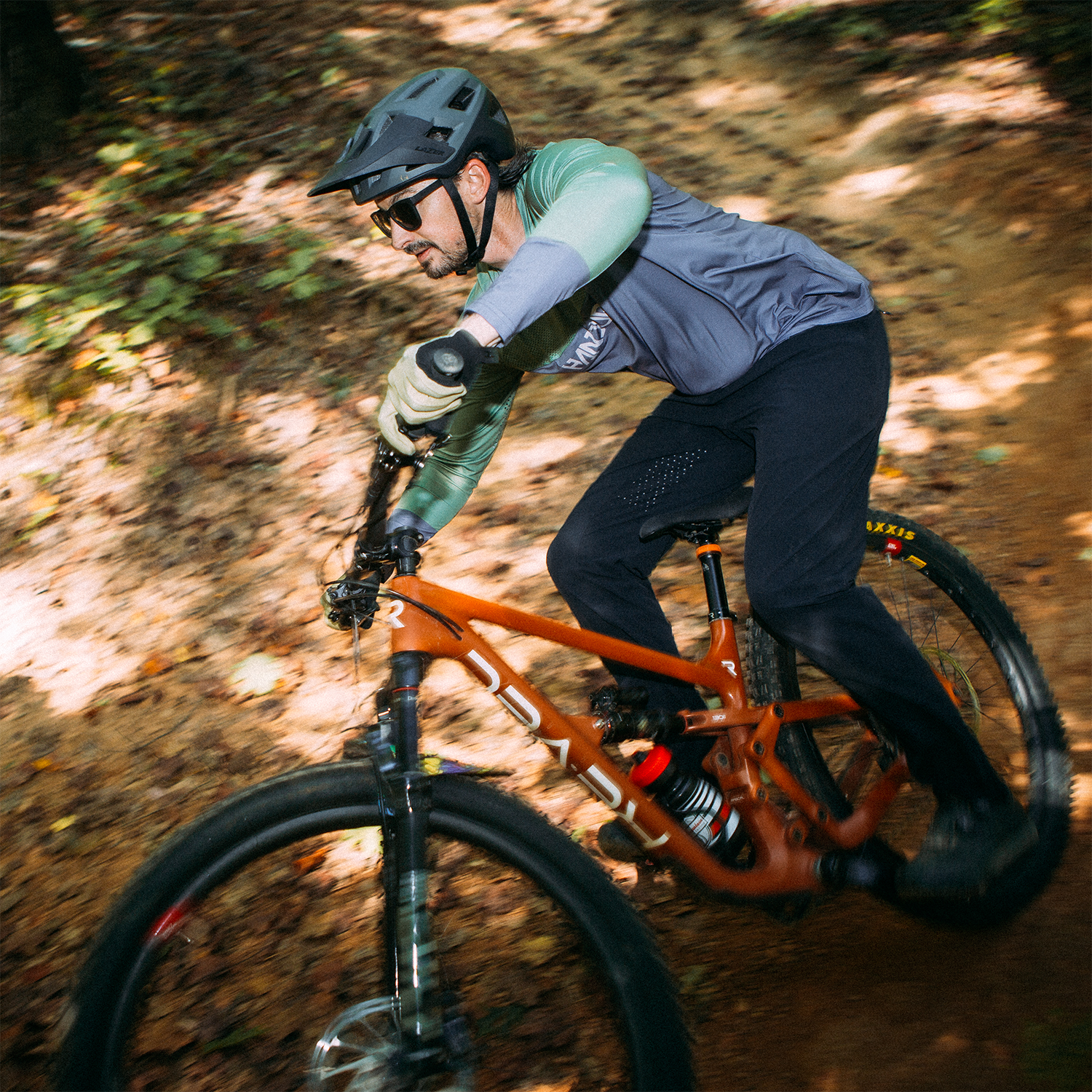 Man riding an orange mountain bike on a forest trail