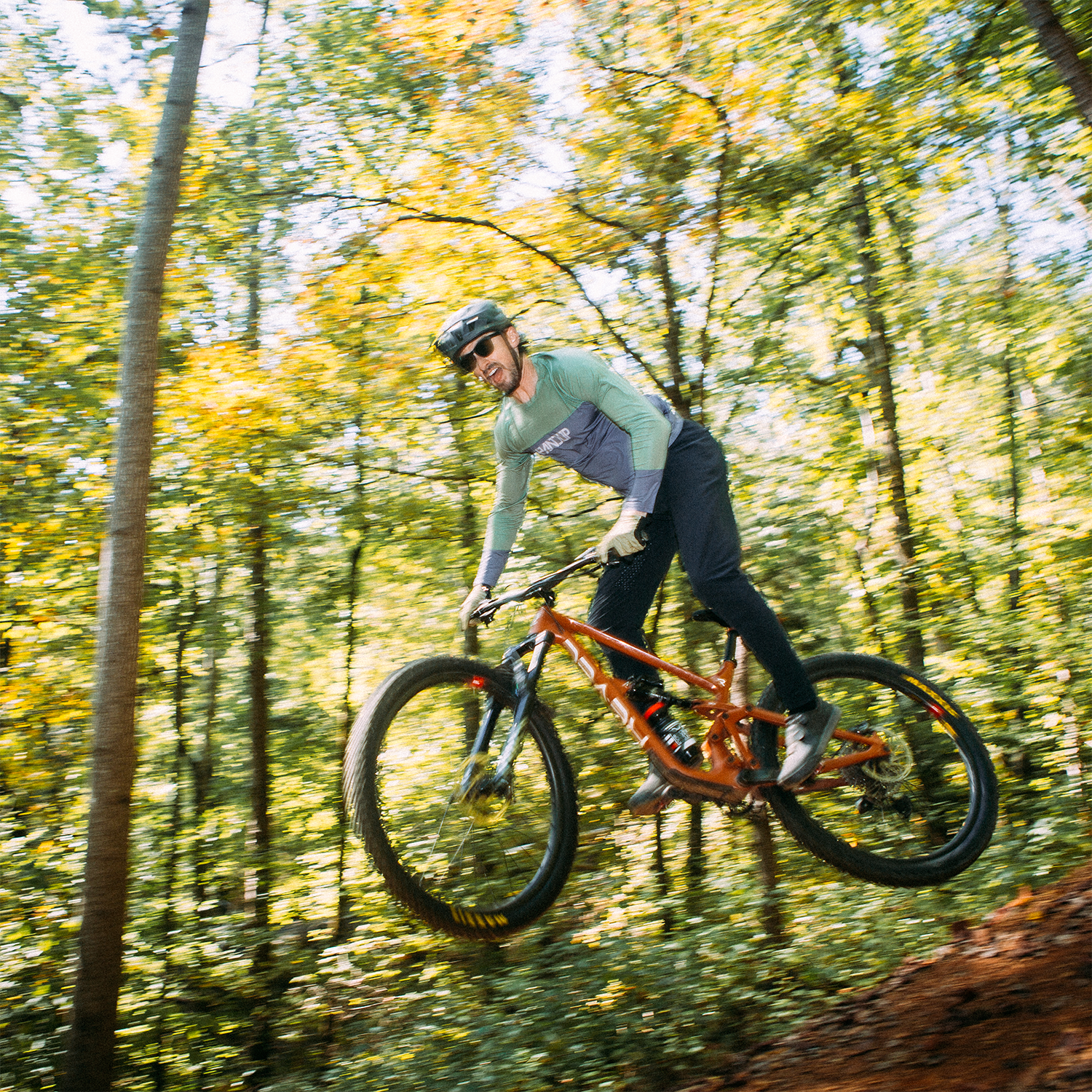 Person riding a mountain bike through a forest with autumn foliage