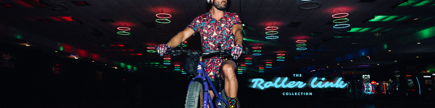 Person riding a bicycle in a dark indoor setting with colorful lights and 'The Roller Link Collection' sign.