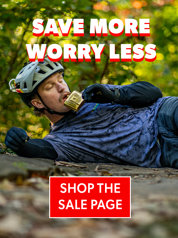 Man lying on a log in a forest with text overlay 'Save More Worry Less' and 'Shop the Sale Page'.