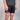 Person wearing black shorts with colorful design on the waistband against a gray background