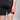 Person wearing black shorts with a colorful bandage on a gray background