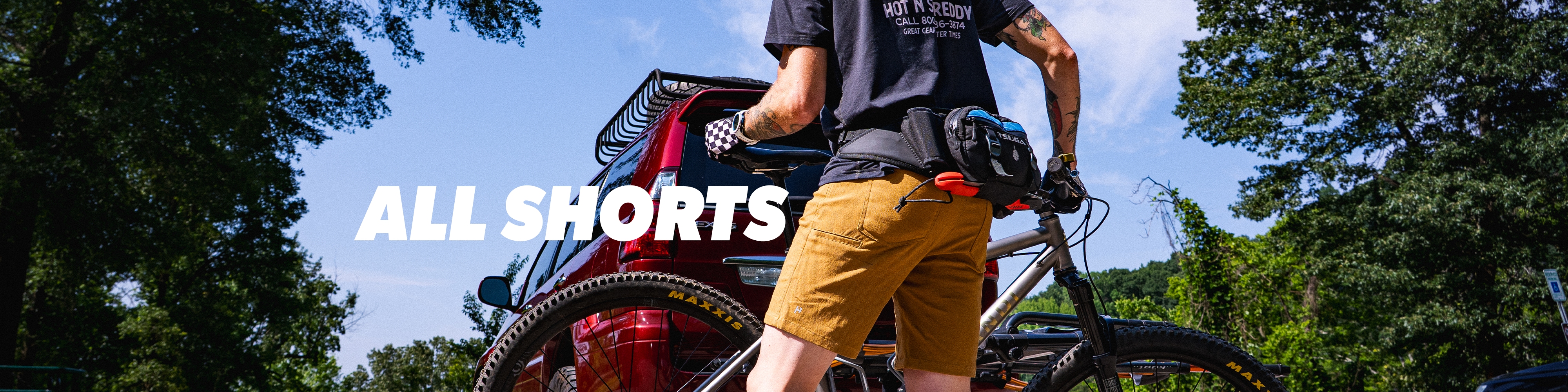 Person with a bike in a natural setting with 'All Shorts' text overlay