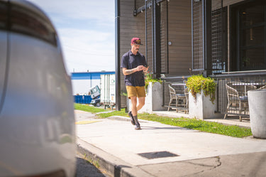 Man walking on a sidewalk near a building with outdoor furniture.