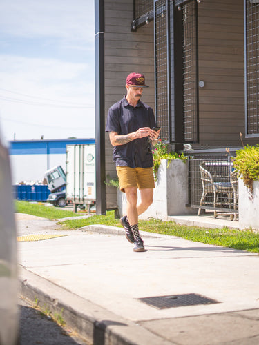 Man walking on a sidewalk near a building with outdoor furniture.