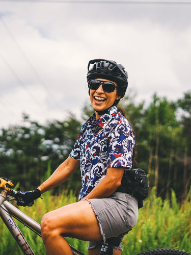 Person riding a bicycle in a natural setting with trees and grass.