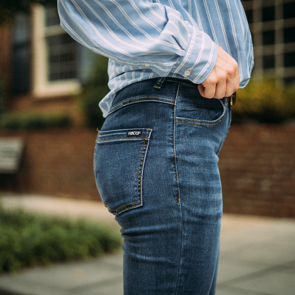 Person wearing blue jeans with a brand logo, standing outdoors.