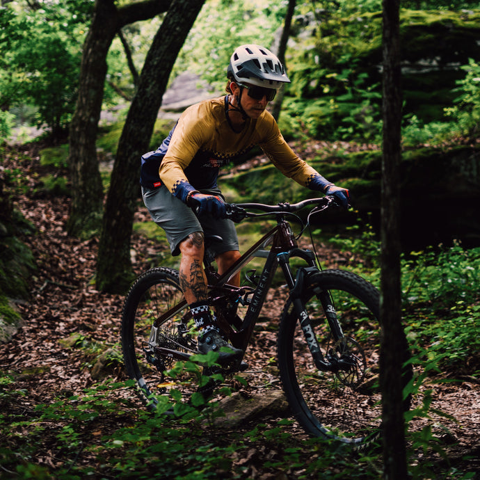 Person mountain biking through a forest trail