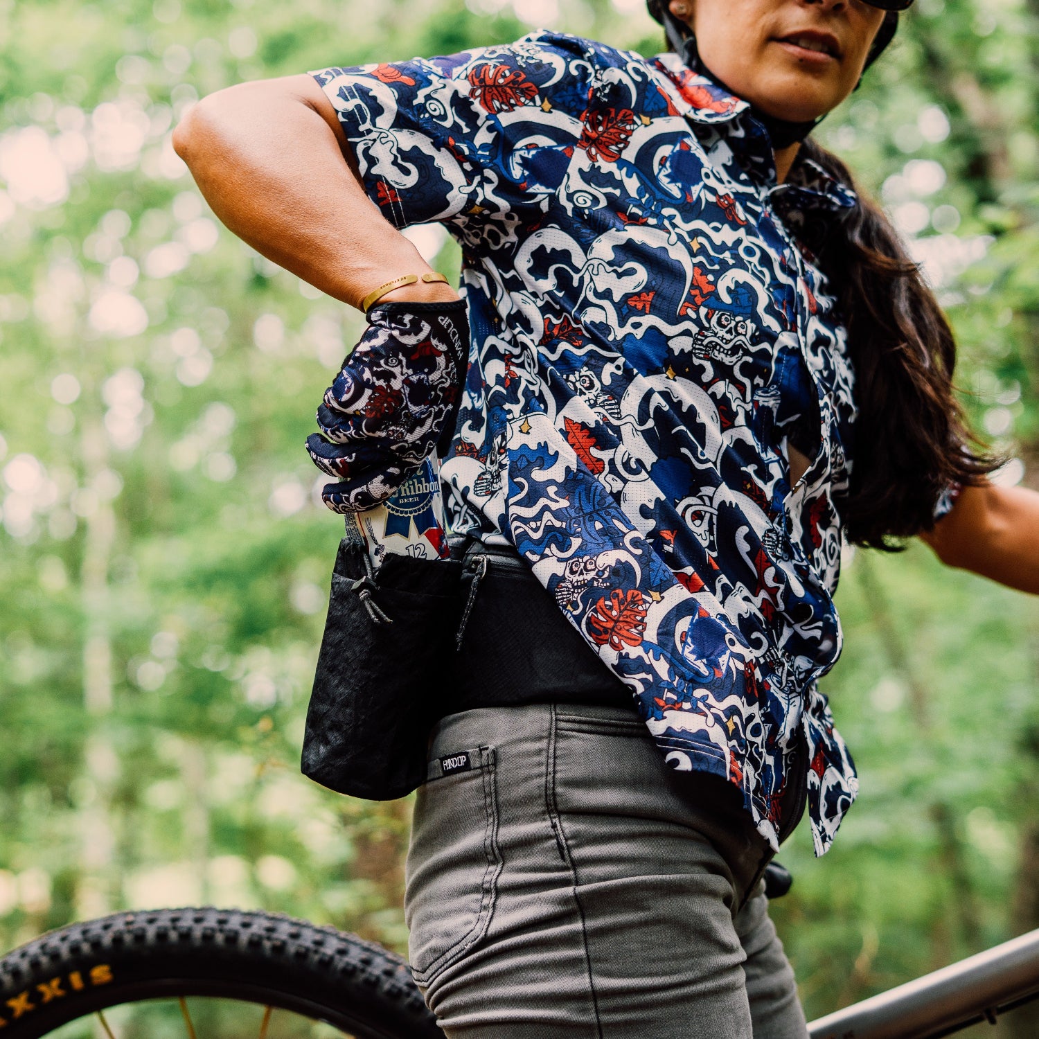 Person wearing a patterned shirt and helmet with a bike in a forest setting