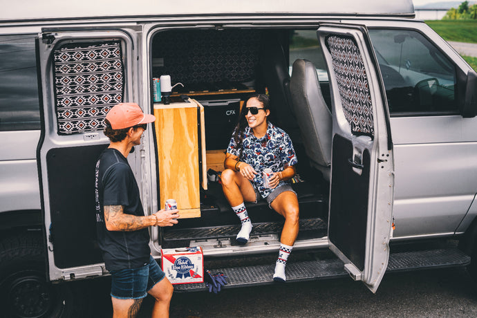 Two people interacting with a van, one inside and one outside, in a casual setting.