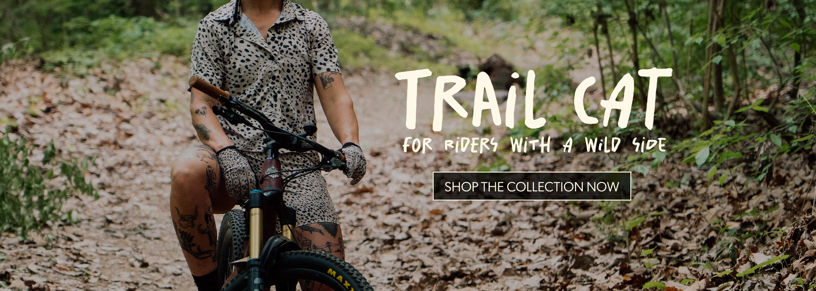 Rider in leopard-inspired mountain bike gear with “Trail Cat” collection branding.