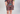A child modeling a matching short-sleeve top and shorts set with a colorful abstract print, standing in a white studio setting.