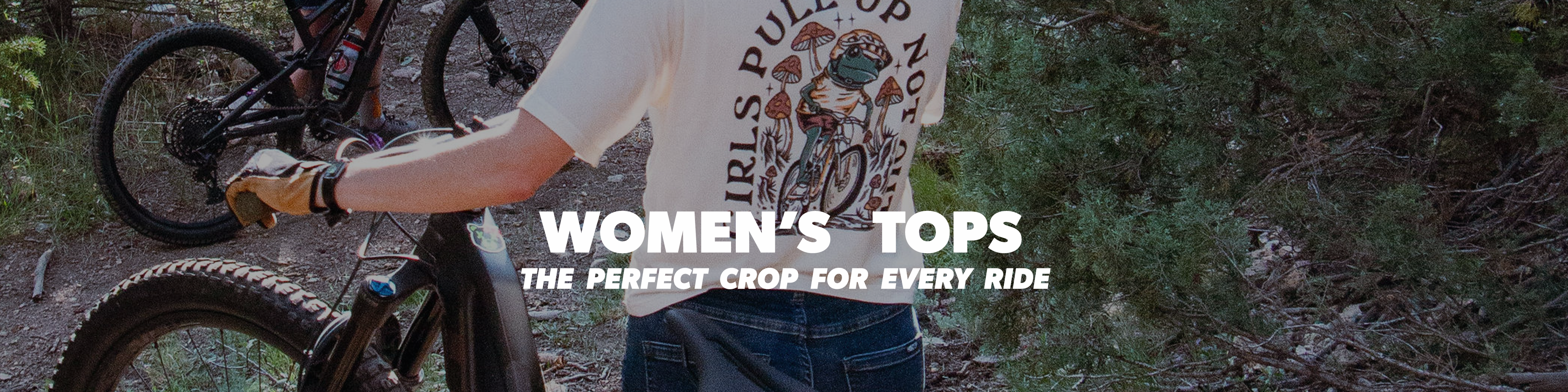 Person holding a bike with text overlay about women's tops in a forest setting