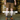 A person wearing brown stretch canvas work shorts, a black t-shirt, gray socks, and brown work boots stands in front of a blurred background of wooden barrels. Large text overlays read 'WORK HORSE STRETCH CANVAS' with a 'SHOP NOW' button below.