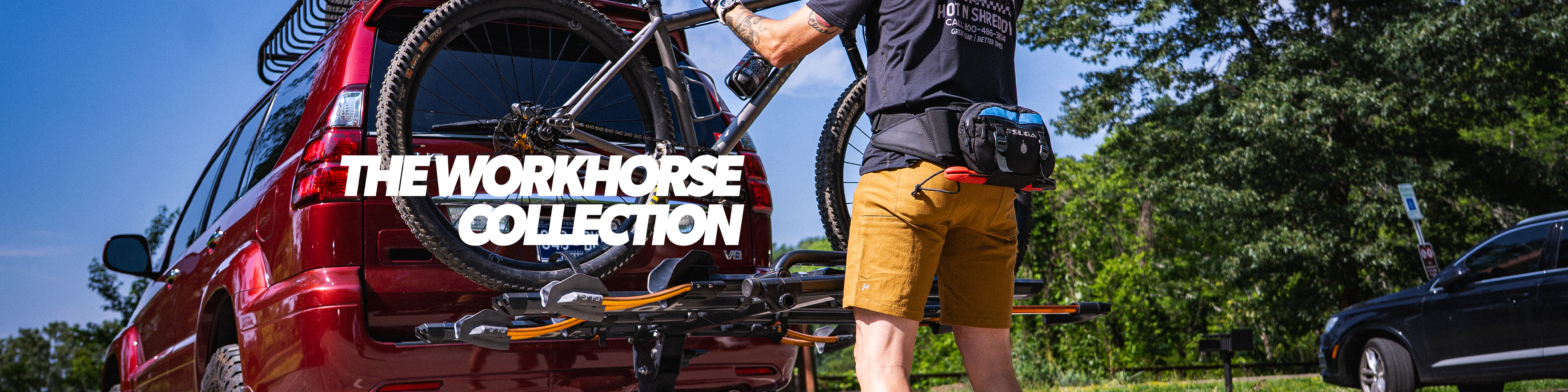 Person loading a bicycle onto a red Workhorse vehicle with trees and a clear sky in the background.