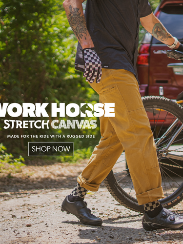Person in checkered gloves and tan pants holding a bike up with promotion text for Workhorse Stretch Canvas pants