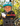 Child wearing a helmet and gloves with 'GO NUTS' branding, holding out a glove towards the camera with a blurred natural background.