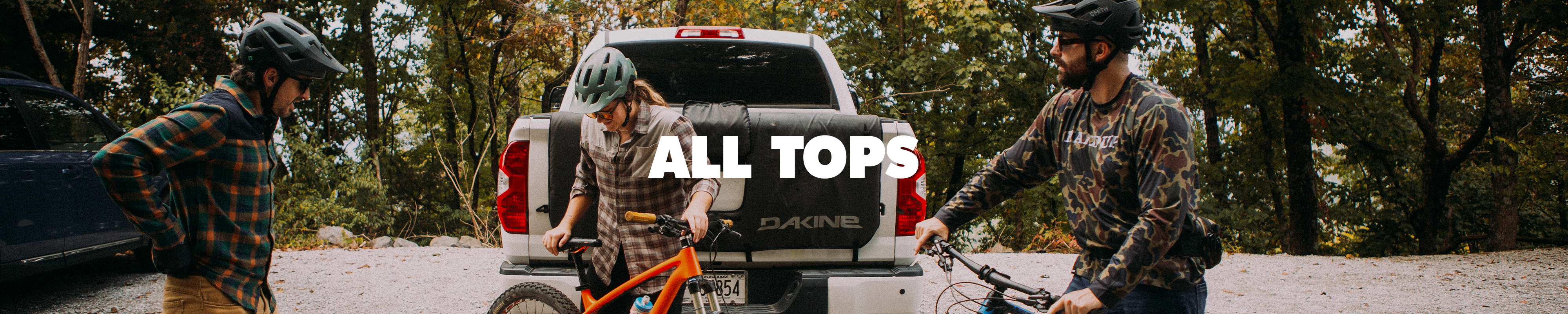 Three people with bicycles and a truck in a forest setting, with 'All Tops' branding.