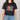 Person wearing a black t-shirt with a graphic design on a plain background