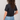 Person wearing a black t-shirt and blue jeans on a plain background