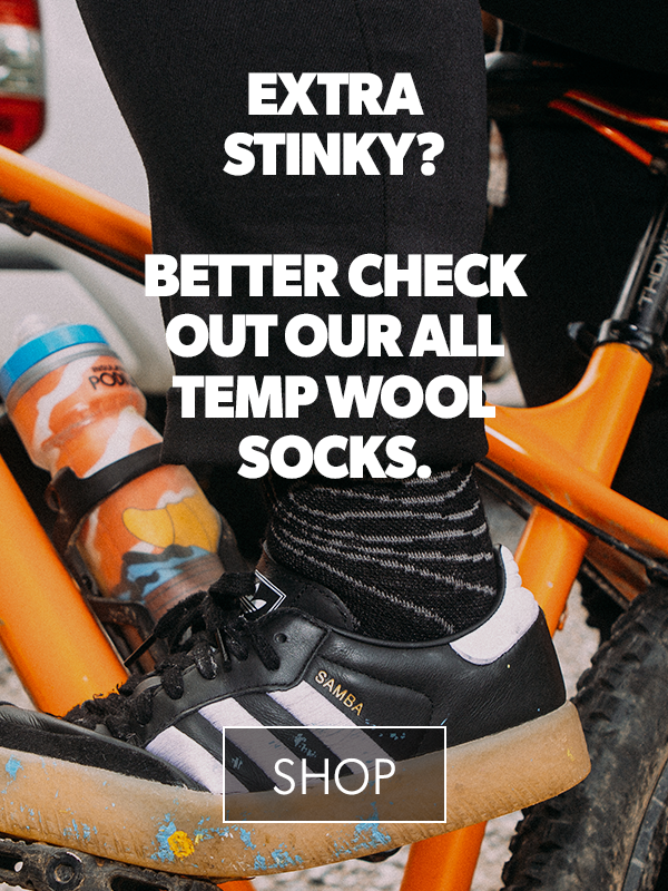 Person wearing black socks with text promoting all-temp wool socks on a bike.